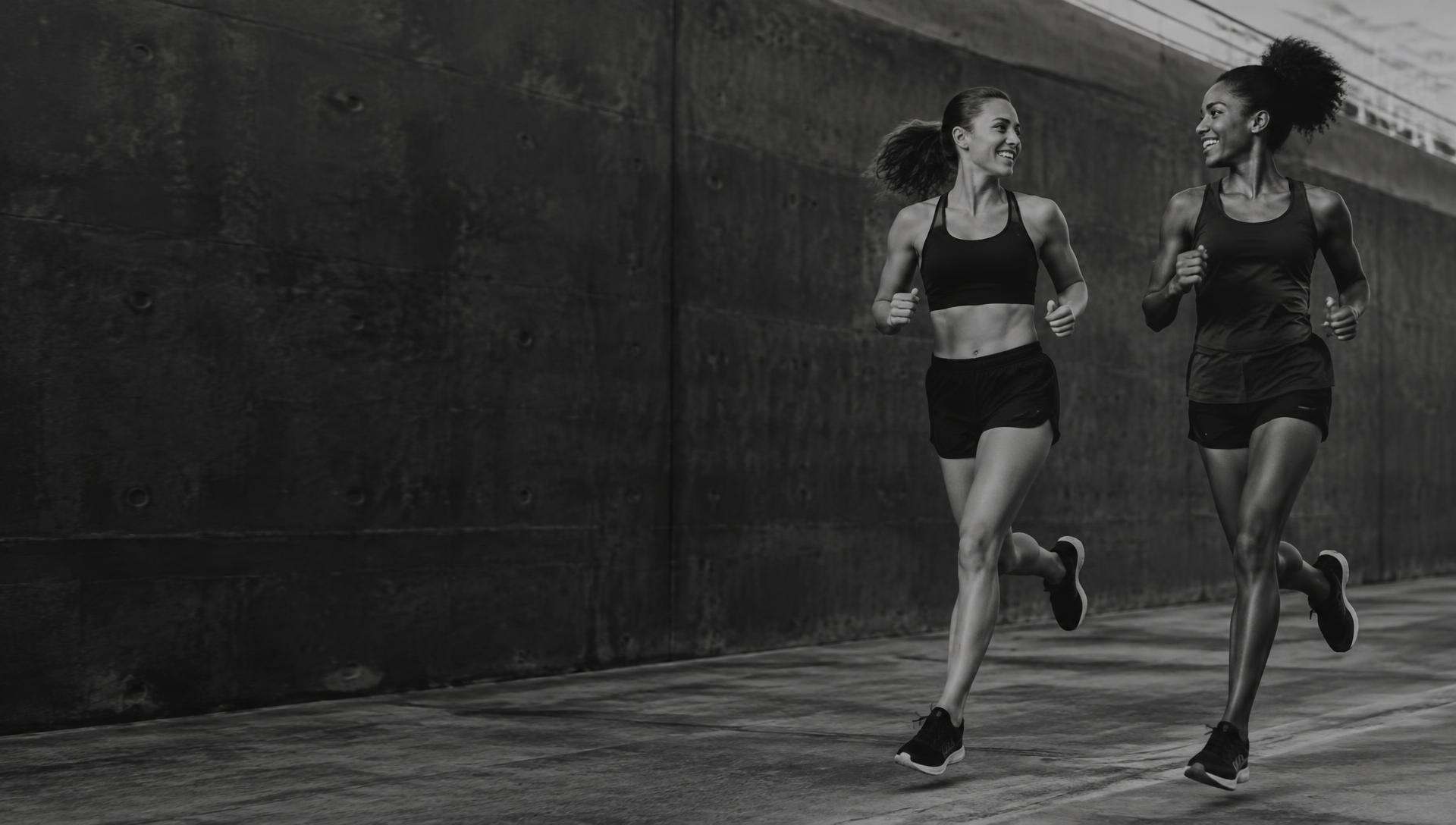 Illustrative editorial photograph of two women running together outdoors